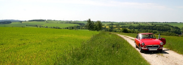 Een rode oldtimer onderweg door de heuvels